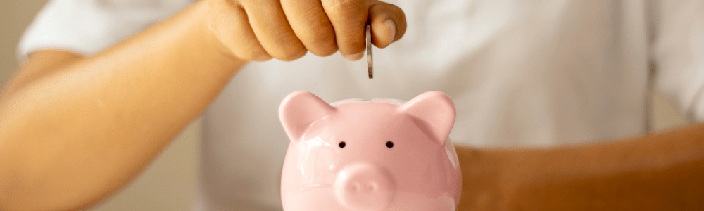 Person Putting Money Into Piggy Bank