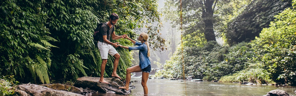 Man Helping Woman Crossing Stream