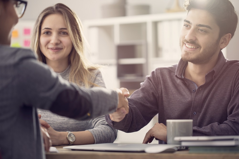 Young Couple Shaking Hands With A Female Agent