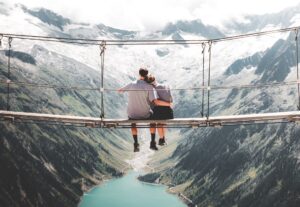 Couple on bridge suspended above a mountain valley