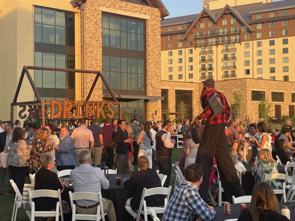 Outdoor gathering with tables and man on stilts