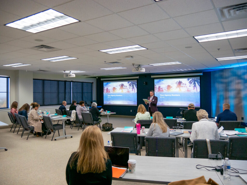 Bill Coyle leading the "Your Agency Numbers" presentation in front of a group of agents