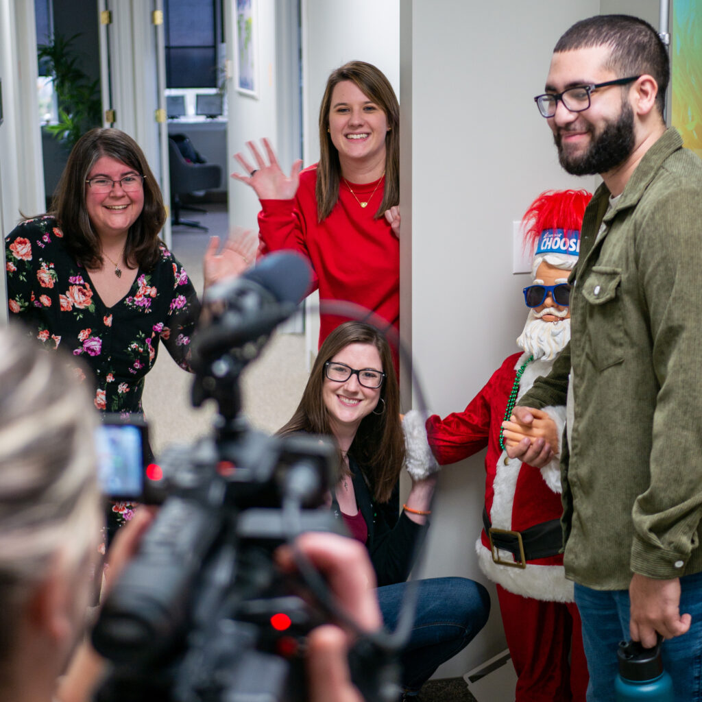 Marketing team members waving and smiling at the camera