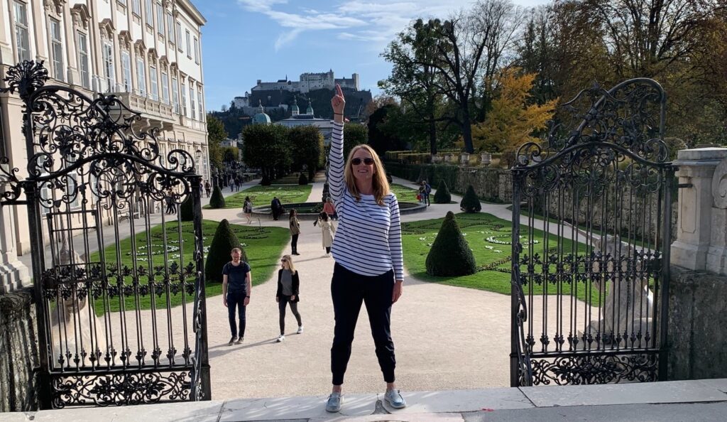 Woman standing in European courtyard pointing to the castle behind her